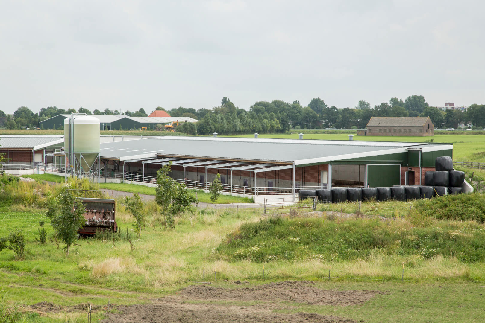 Het vooraanzicht van een Dijkstal. De drink en mestruimte is deels overdekt en de ruimte met sorteerunit en voerbakken is geheel overkapt. 